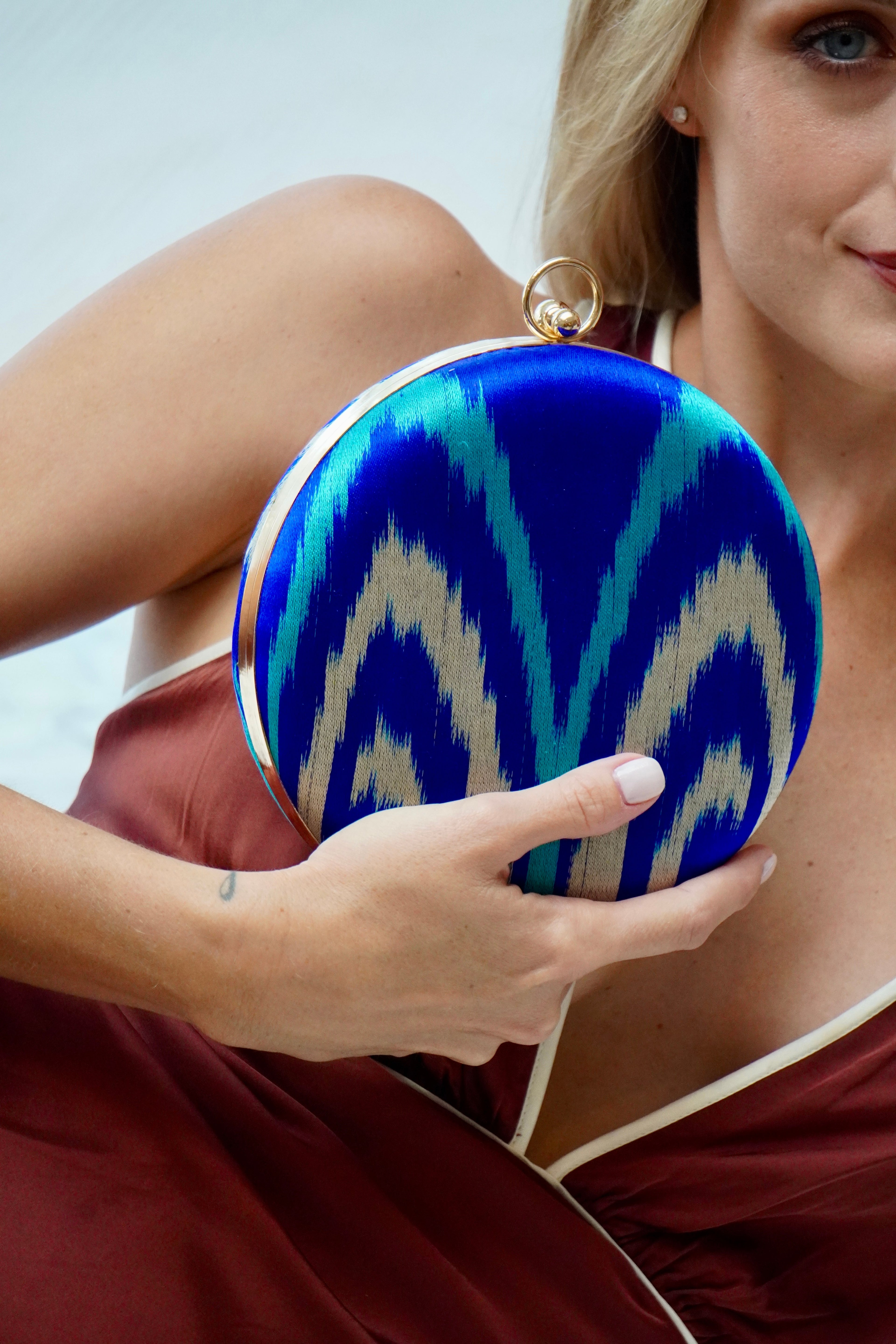 Woman holding a blue and gold patterned silk ikat handwoven clutch