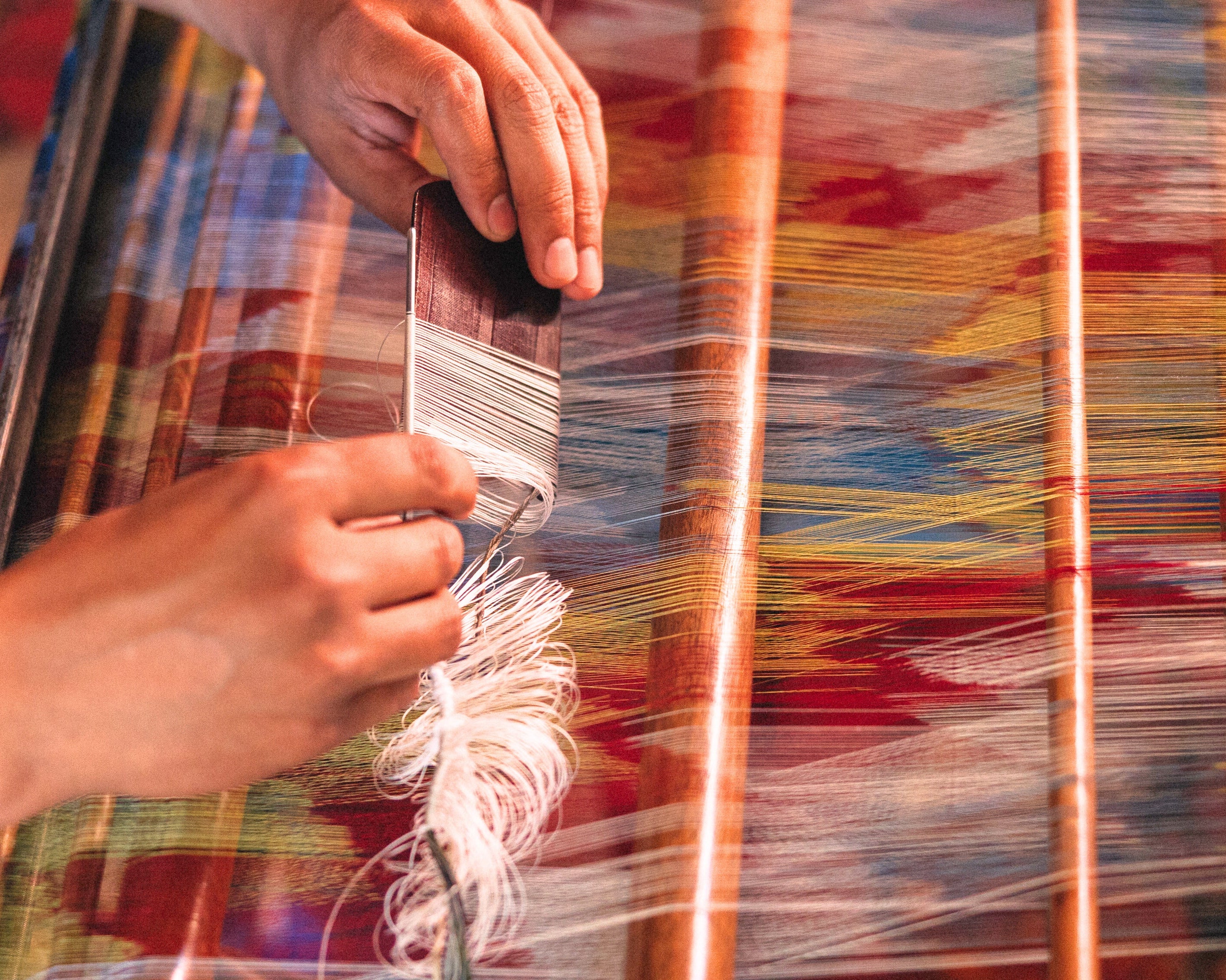 Person weaving with colorful yarn on a loom