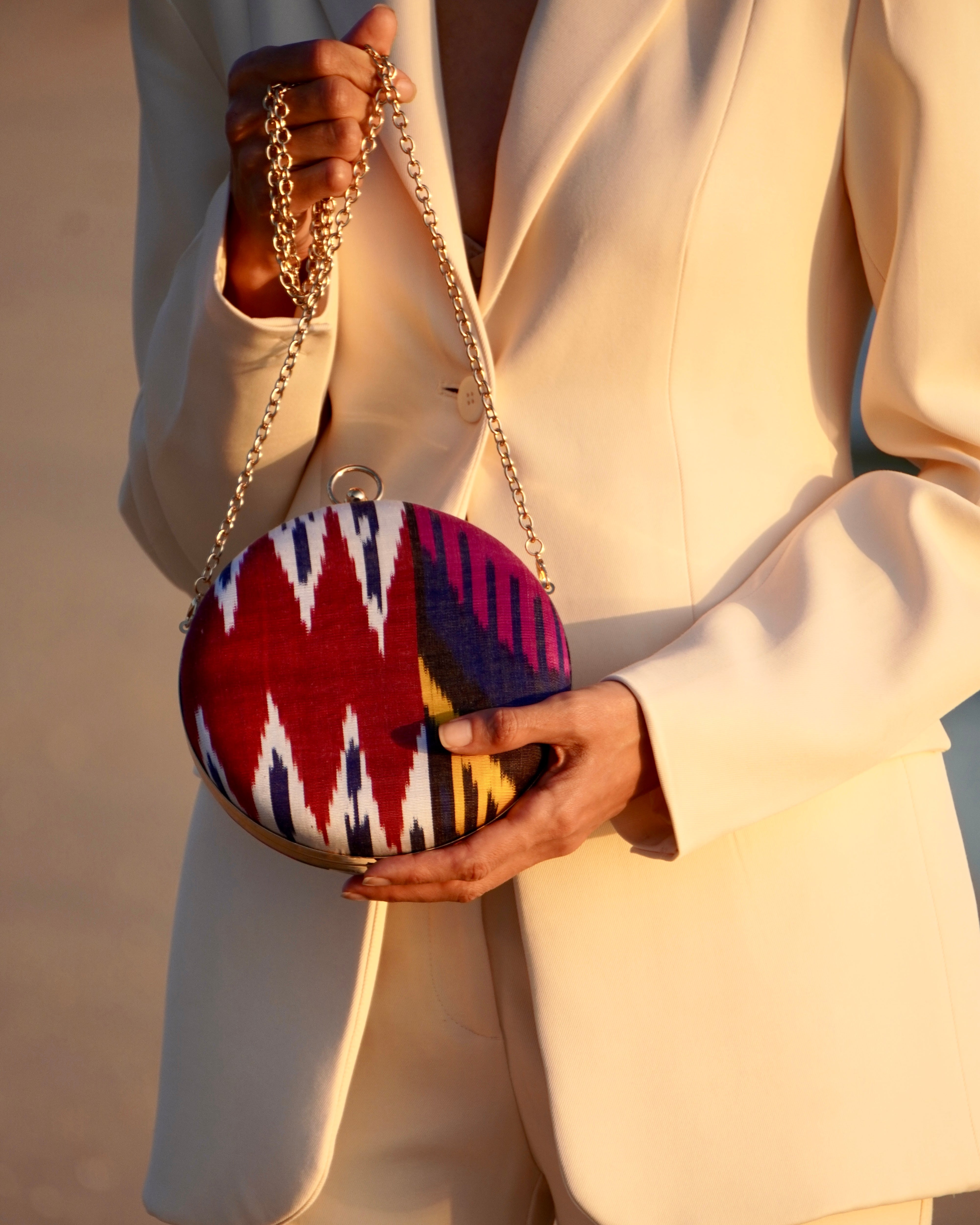 Woman holding a colorful Frankitas contemporary round silk ikat artisan clutch handbag