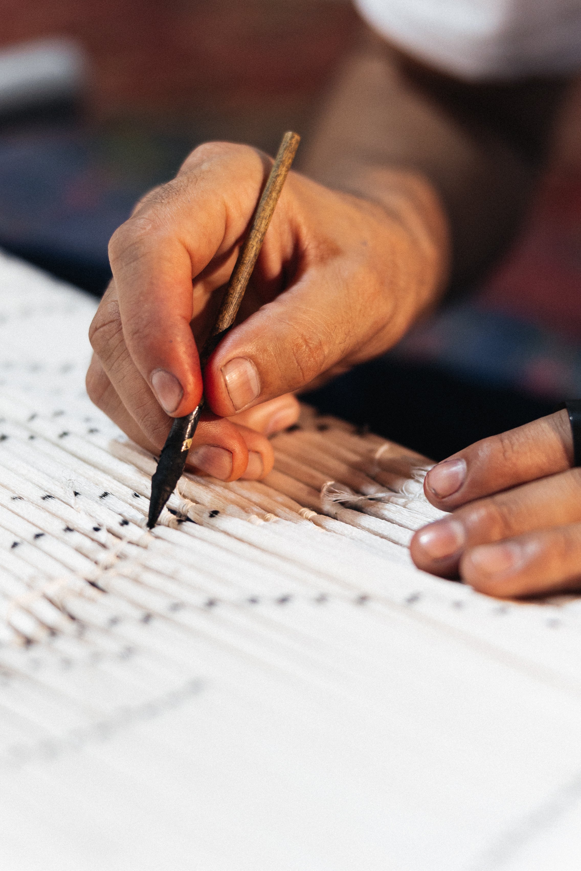 Hand holding a pen over the creation of Silk Ikat patterns for Frankitas handwoven silk ikat handbags and clutches