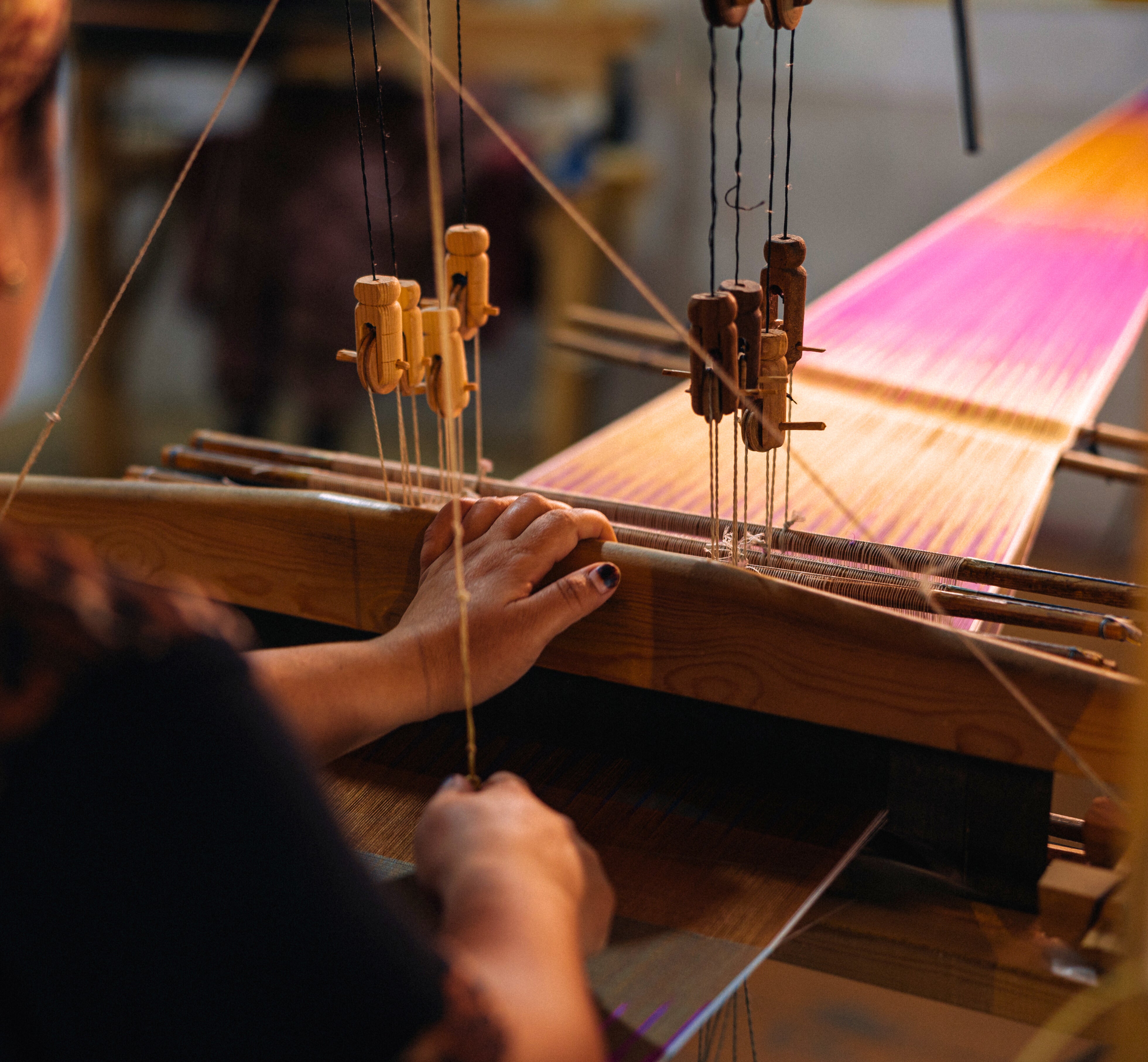 Person weaving on a loom with colorful fabric silk ikat for Frankitas handbags and clutches