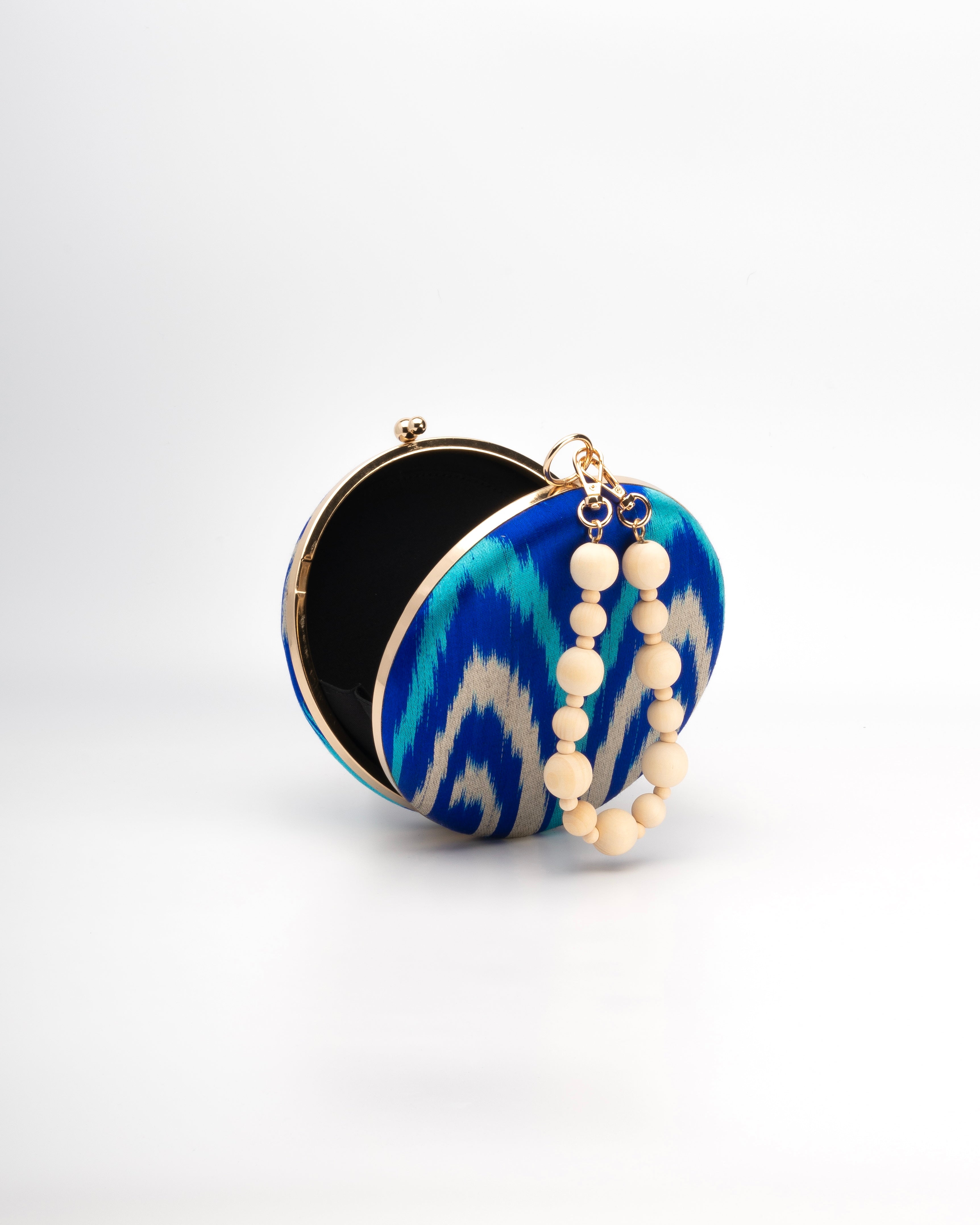Frankitas Puteri handbag clutch  featuring blue, turquoise and beige triba patterned handwoven silk ikat with a light wood beaded strap
