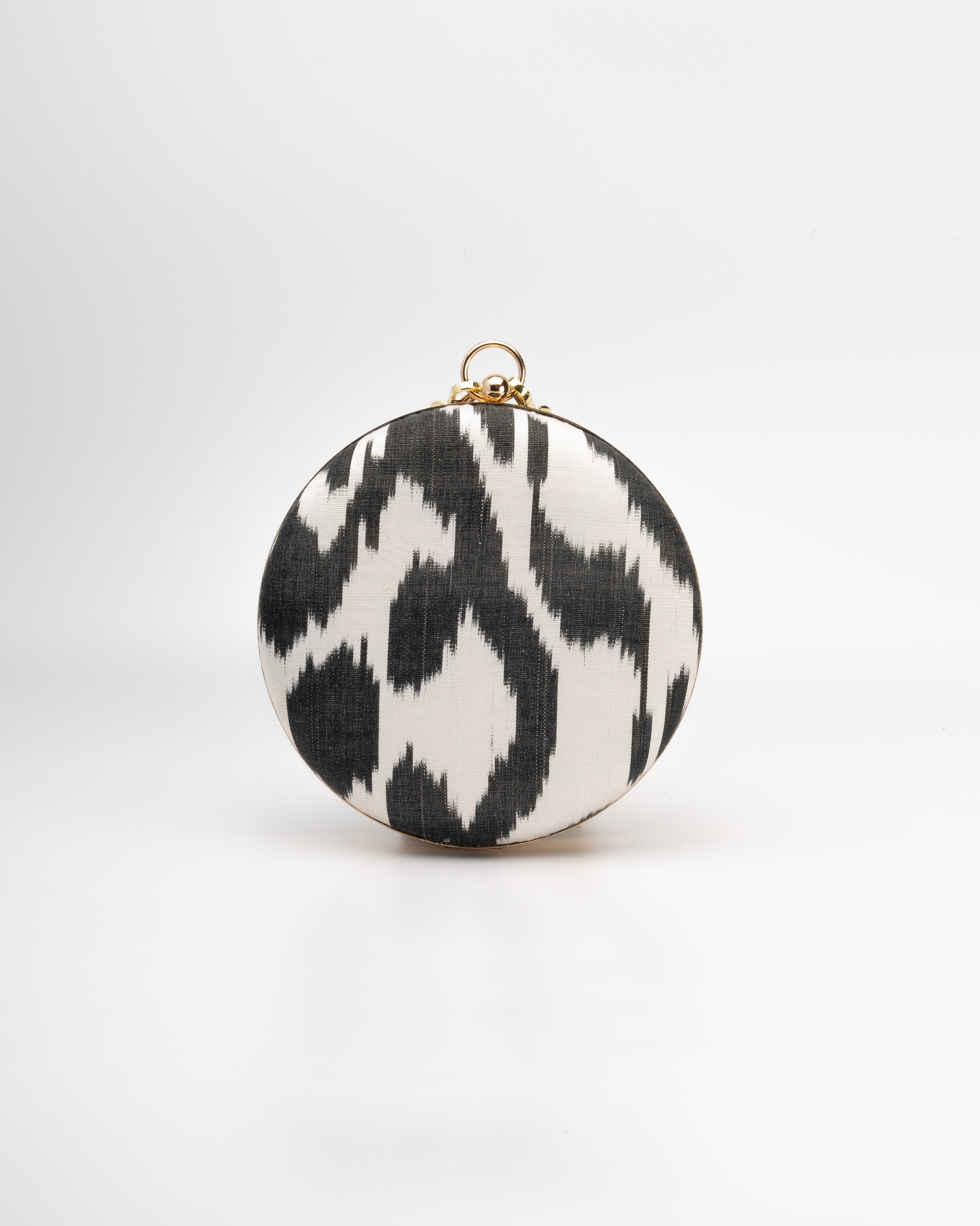 Round Frankitas Puteri clutch bag featuring artisan-woven silk Ikat in a classic black and white with cultural motifs
