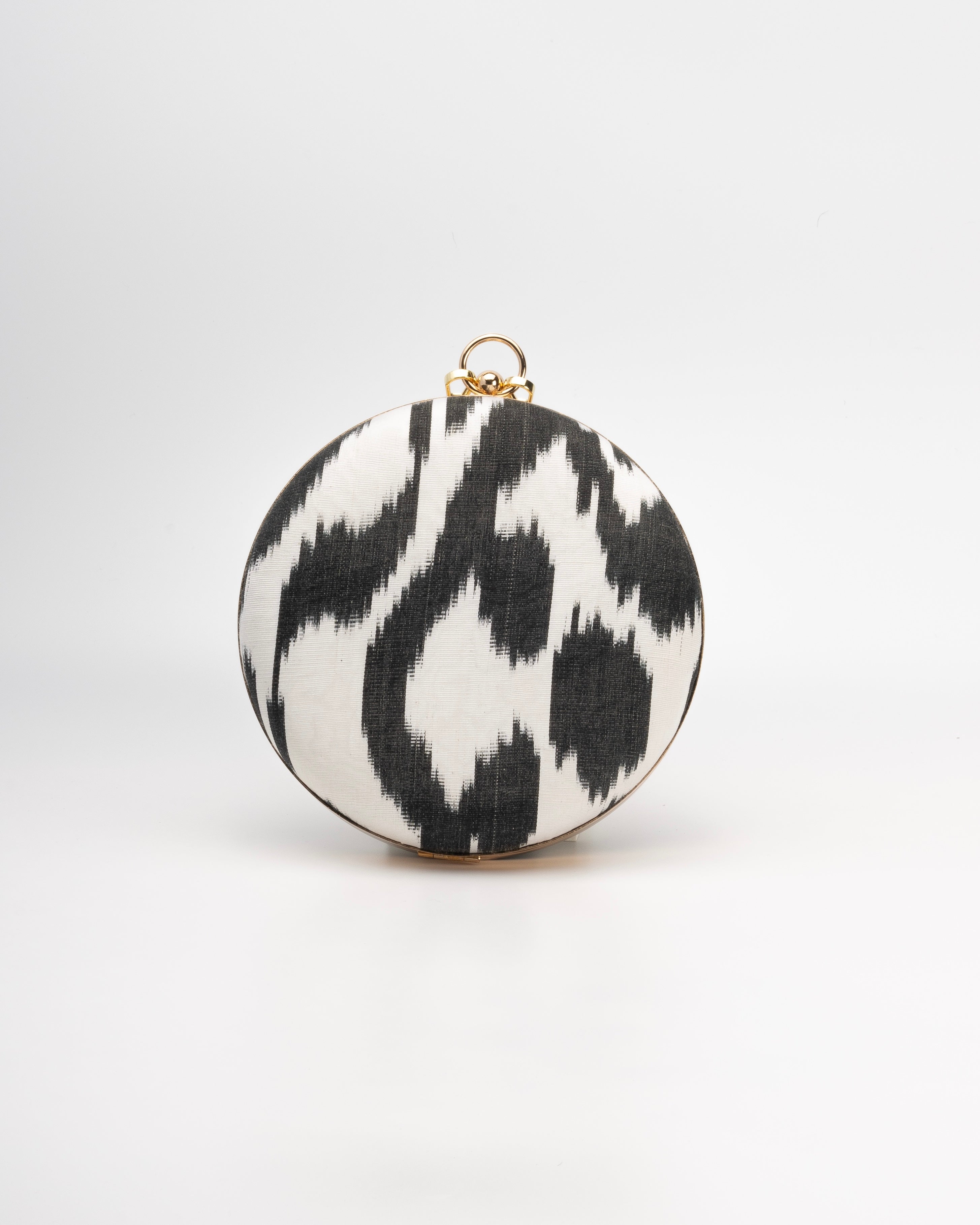 The Puteri round clutch by Frankitas, a sleek silhouette adorned with vibrant handcrafted silk Ikat