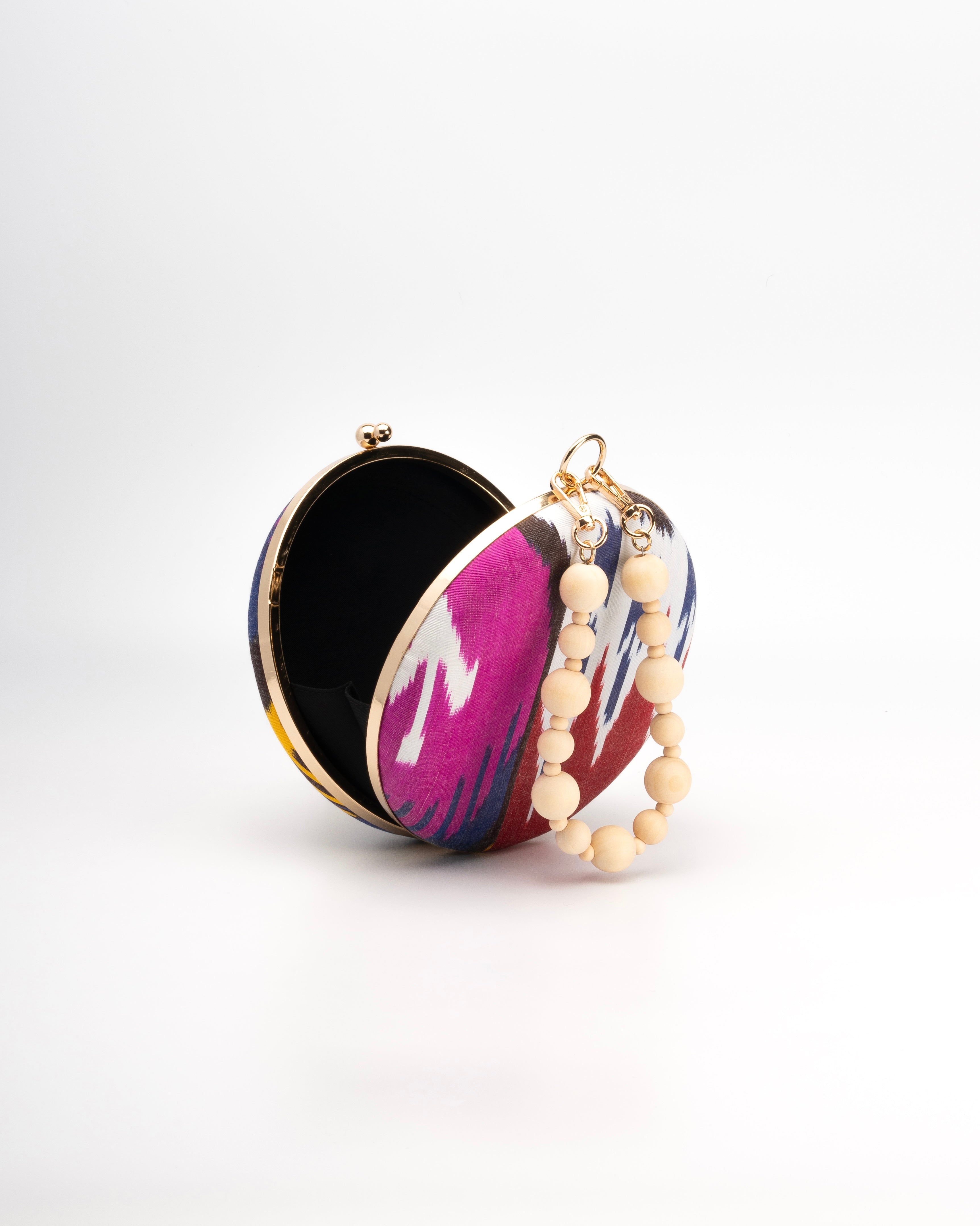 A blend of tradition and style, Frankitas' Puteri Round clutch showcases a colorful silk ikat weave pattern paired with a wooden beaded strap