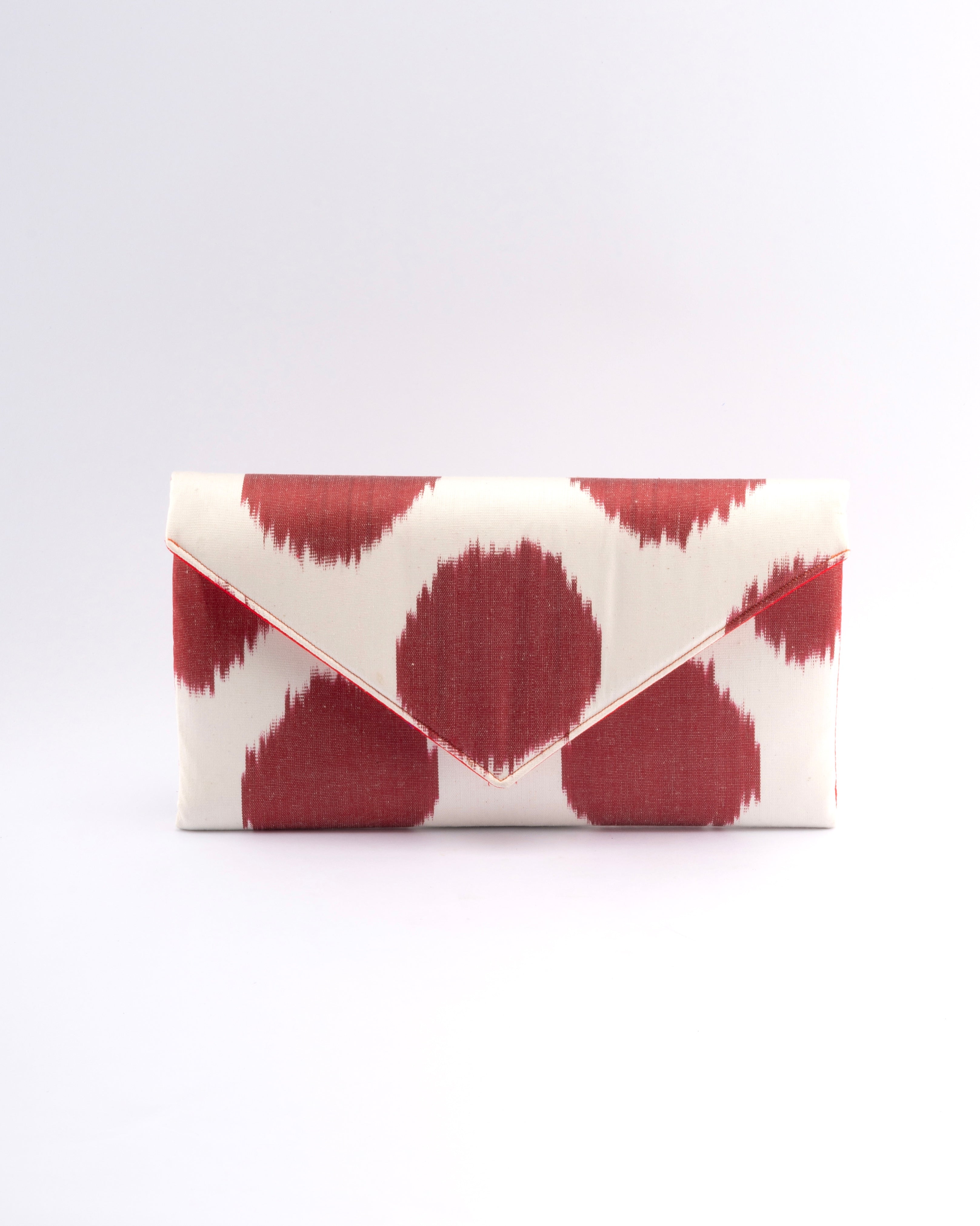 Merging tradition with elegance, Frankitas' classic envelope clutch highlights the beauty of handwoven silk ikat in a red and white polka dot design