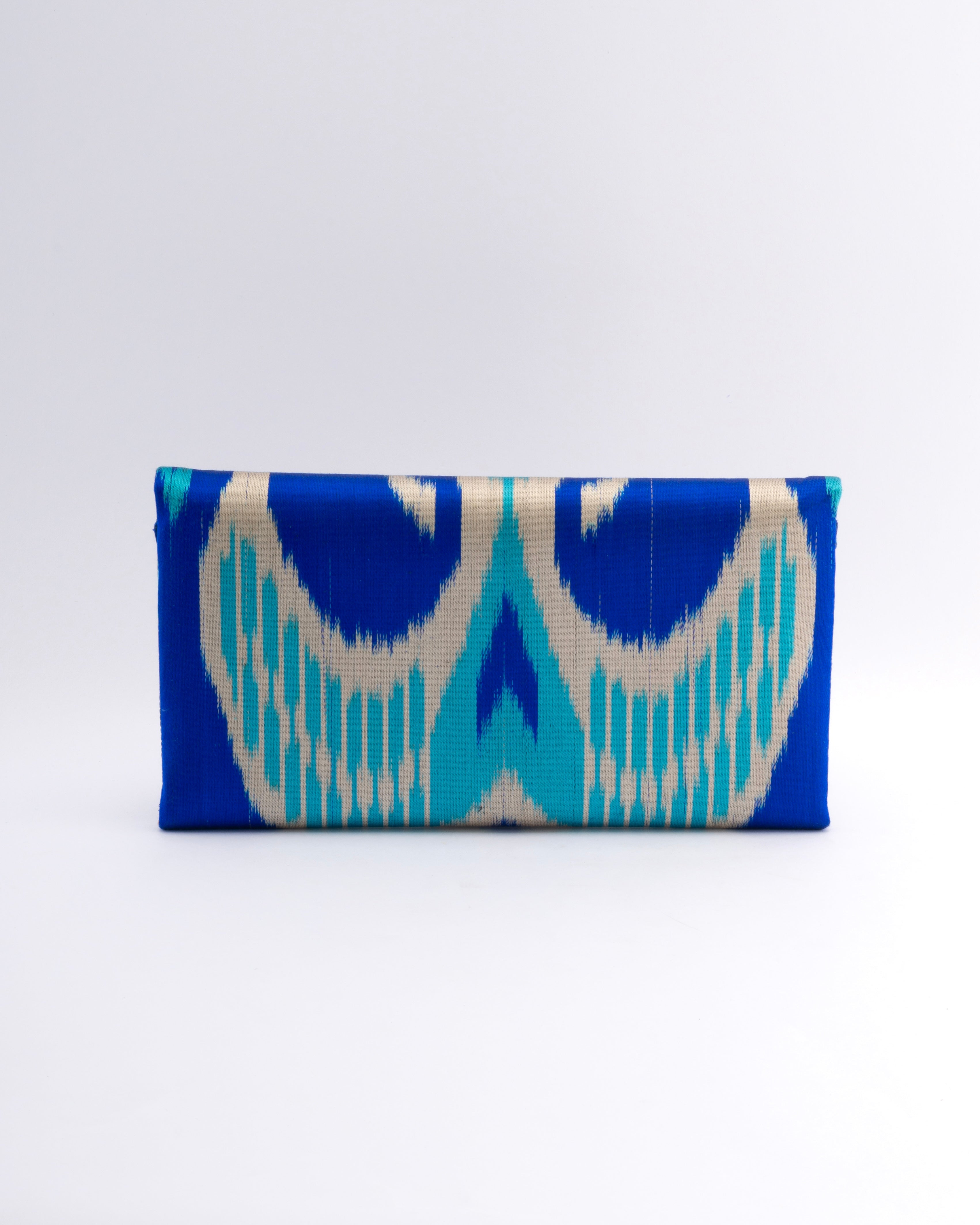 The beauty of handwoven silk ikat featured on a Frankitas Titin clutch with a deep blue, turquoise and beige pattern handwoven by artisans in Central Asia