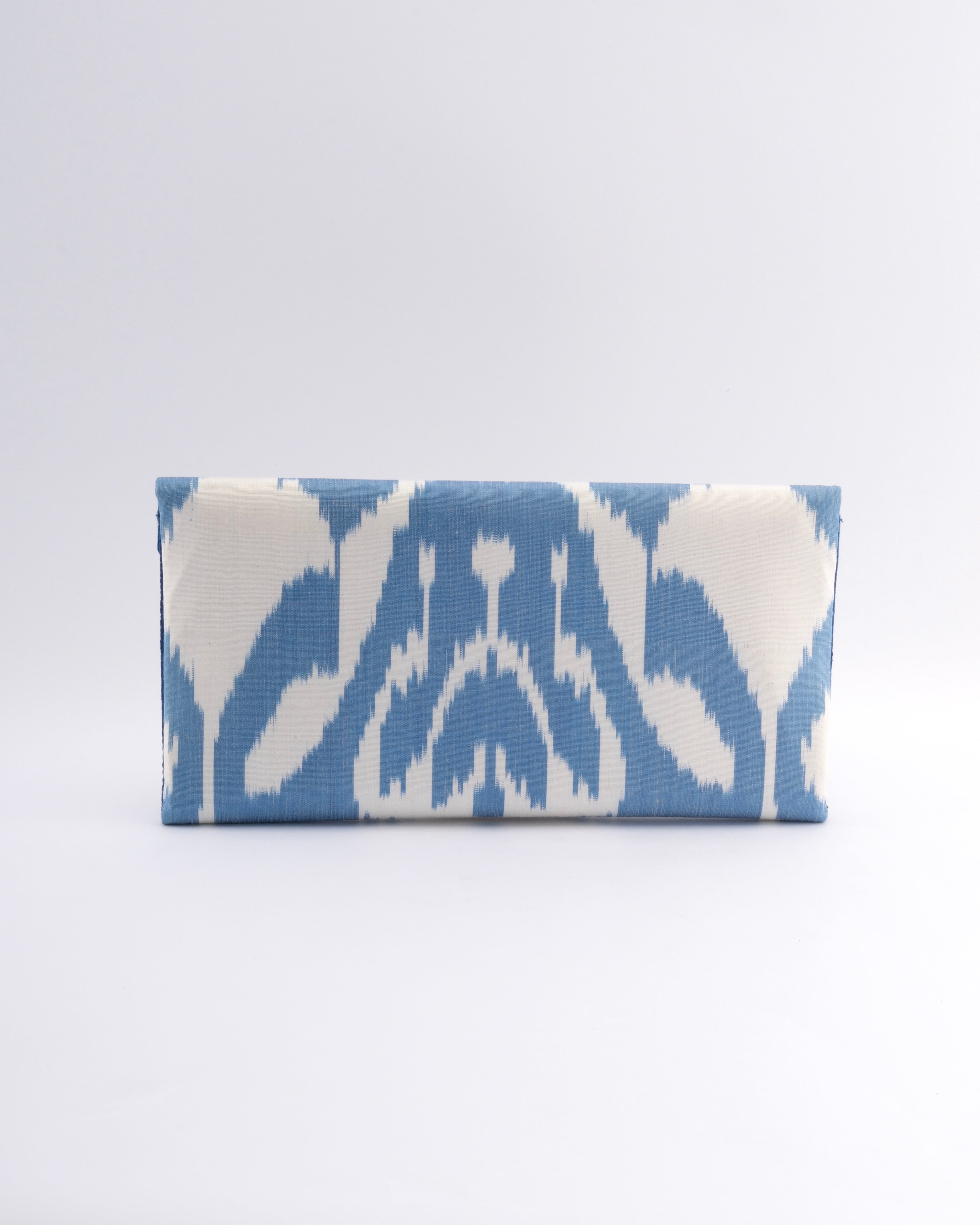 A classic envelope clutch by Frankitas featuring handwoven silk ikat a sustainable eco-friendly fabric in Blue and white tribal flower design