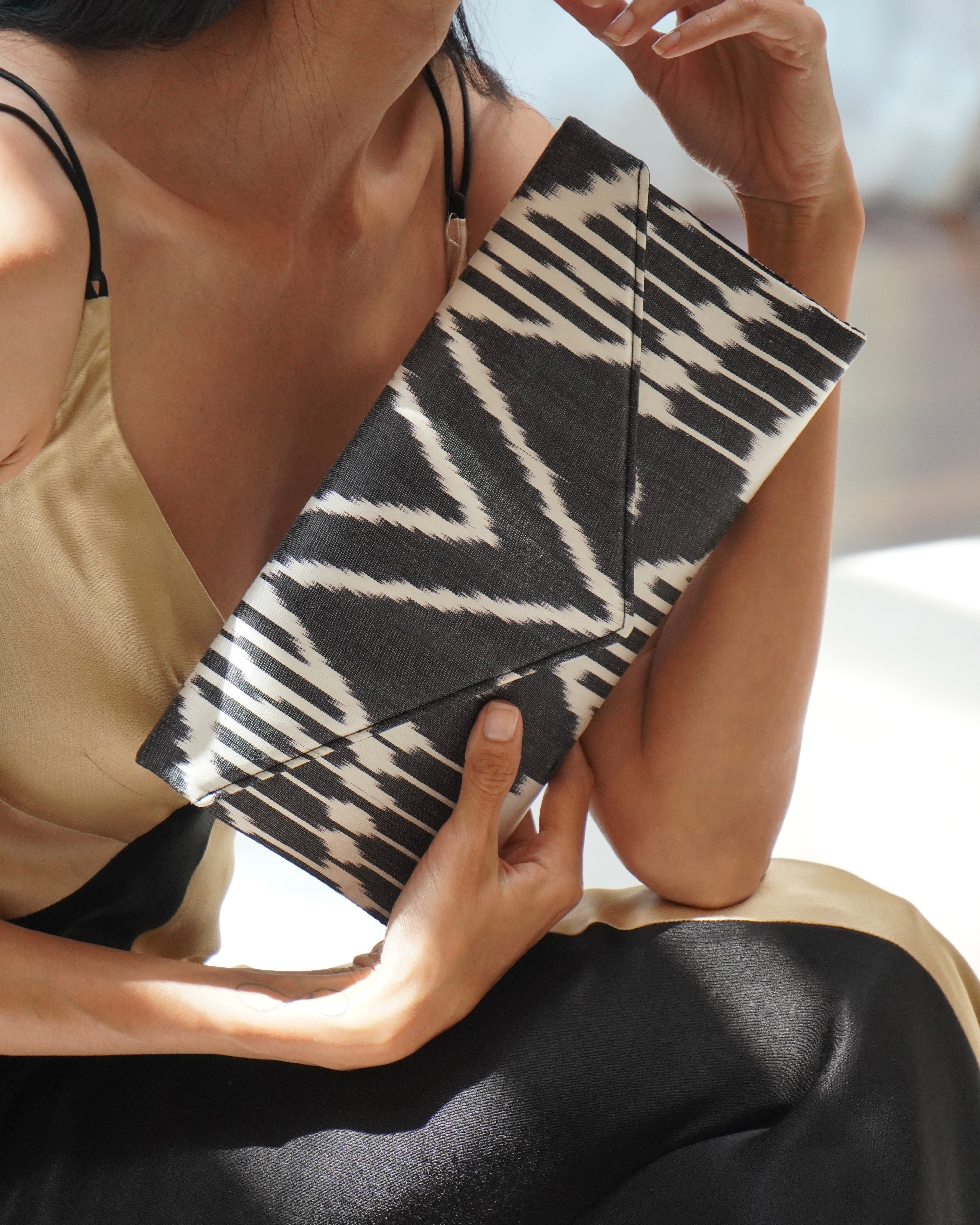 Woman holding a Frankitas silk ikat handwoven zebra-striped  black and white clutch bag